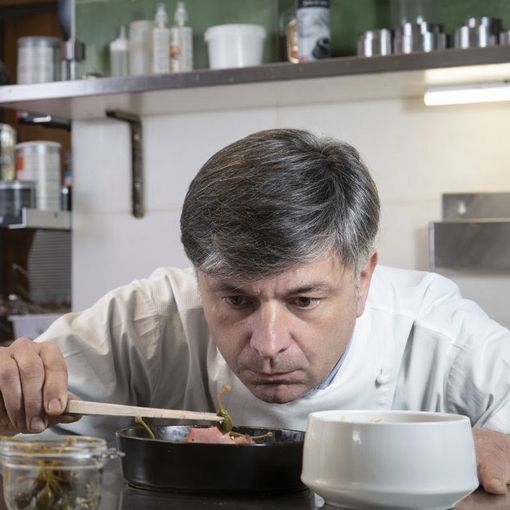 Cuoco che assaggia da una pentola con un cucchiaio di legno