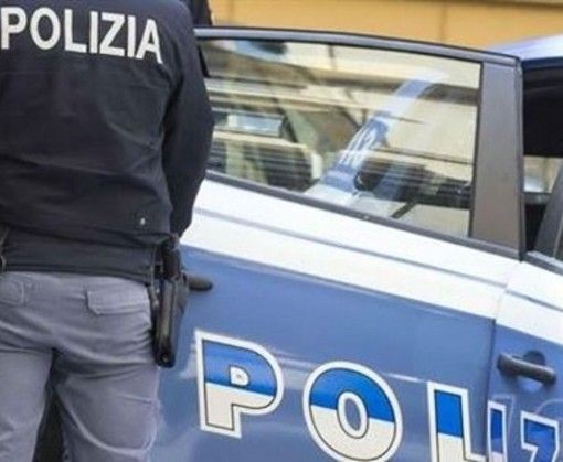 auto della POlizia con agente in piedi vicino a una portiera aperta