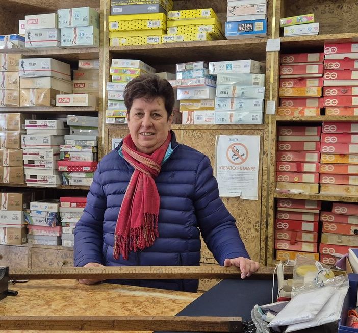 Caterina Ferrero nel suo negozio con in mano uno storico metro in legno per tessuti