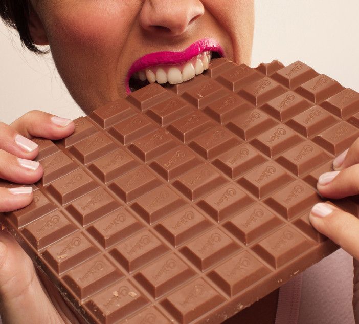 persona che morde una tavoletta di cioccolato