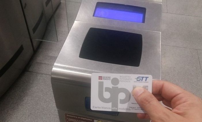 mano mostra abbonamento gtt bip card davanti all'ingresso della metro