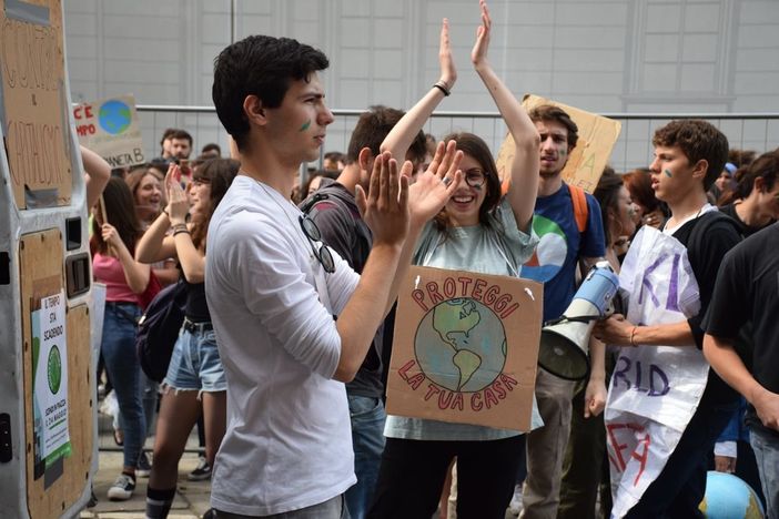 ragazzo davanti ad altri manifestanti con cartelli