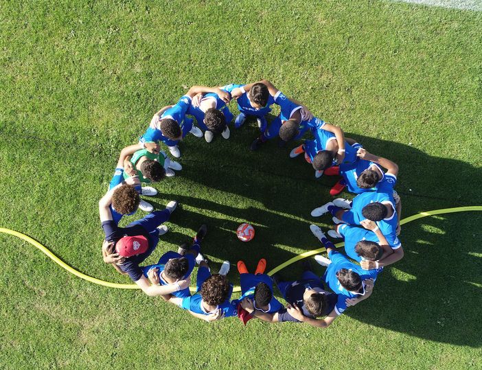 ragazzi abbracciati in mezzo al campo di calcio