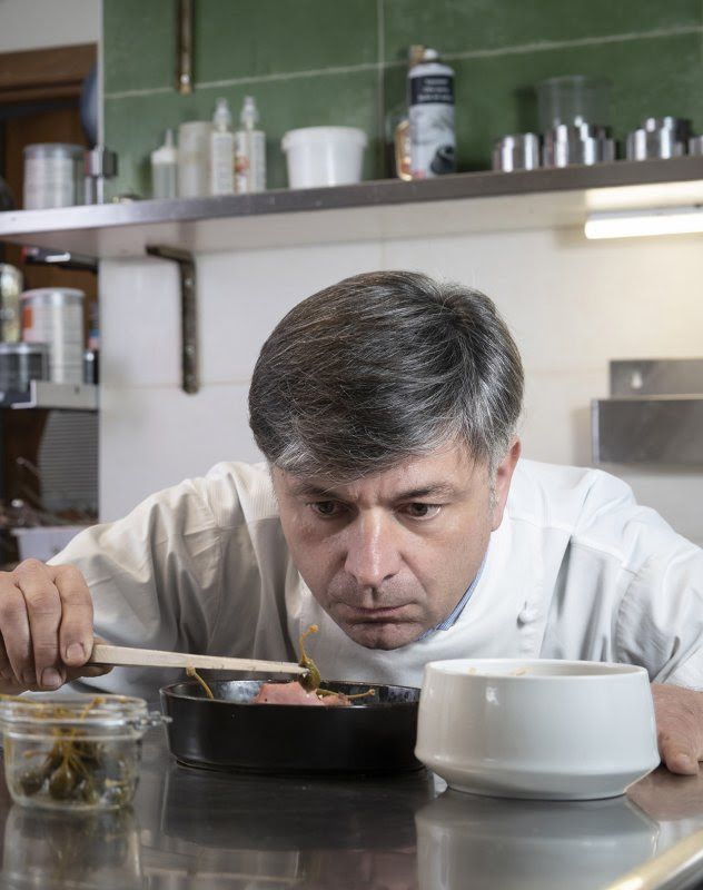 Cuoco che assaggia da una pentola con un cucchiaio di legno Cuoco che assaggia da una pentola con un cucchiaio di legno
