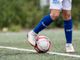 Gambe di un calciatore che toccano un pallone