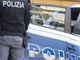 auto della POlizia con agente in piedi vicino a una portiera aperta