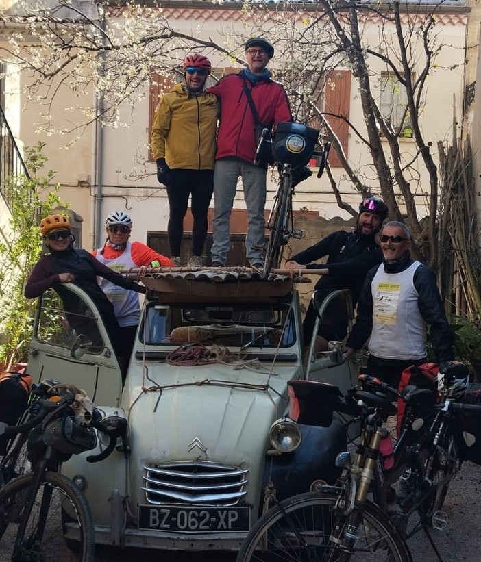 Davide Rivoira con i compagni di viaggio, a sinistra, sul tettuccio della Citroën dell’artista di Arles